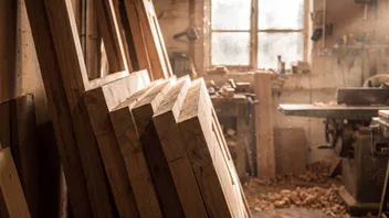 Timber door linings stacked on edge in a joinery workshop, end grain towards the camera