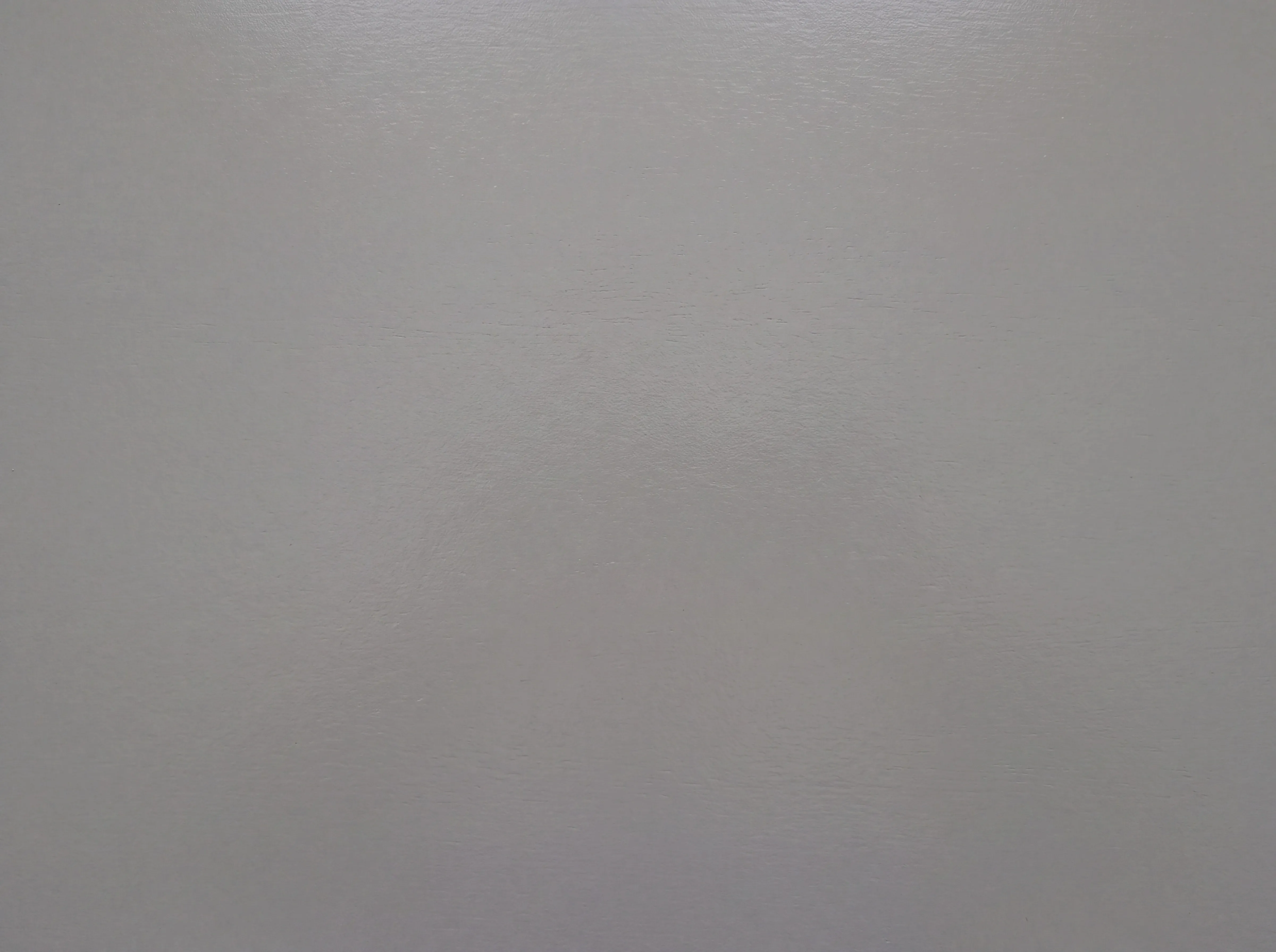 A macro study of a mid-grey painted timber panel with an eggshell sheen